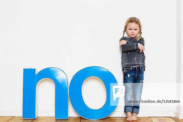 Junges Mädchen steht neben großen dreidimensionalen Buchstaben  die das Wort NEIN buchstabieren