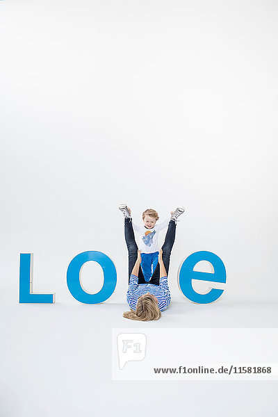 Mother and son lying on floor between three-dimensional letters  creating the word LOVE