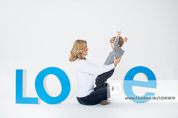 Mother and son sitting between three-dimensional letters  creating the word LOVE