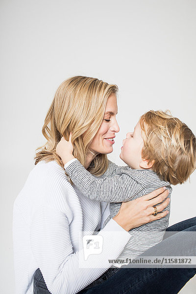 Portrait of mother and son against white background  face to face  smiling