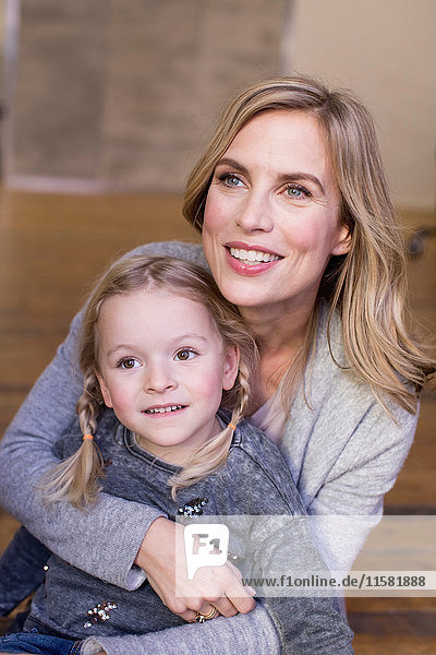 Portrait of mother and daughter  sitting on floor  smiling