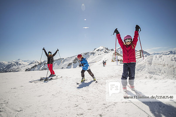Full length of family enjoying while skiing against clear sky