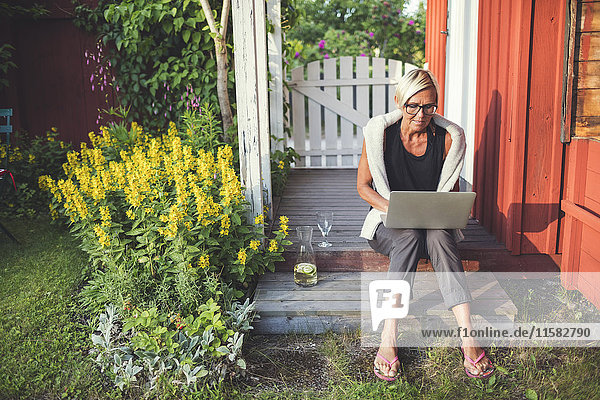 Frau mit Laptop im Garten an einem sonnigen Tag