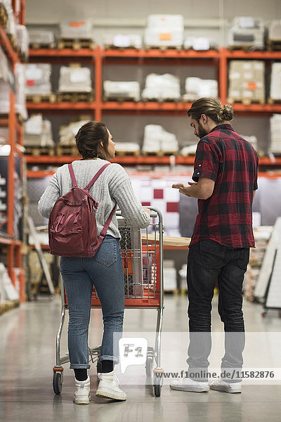 Full length rear view of couple discussing while walking in hardware store