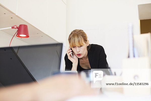 Mid adult businesswoman talking on mobile phone in office