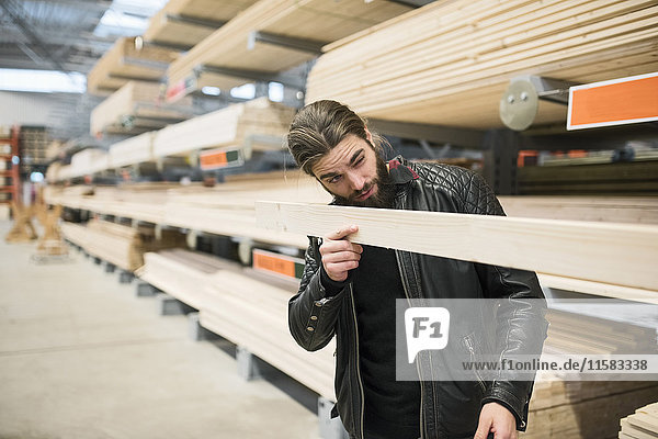 Männlicher Kunde untersucht Holzbohle im Baumarkt