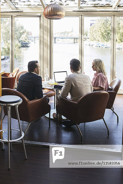 Business colleagues sitting with laptop during meeting at restaurant
