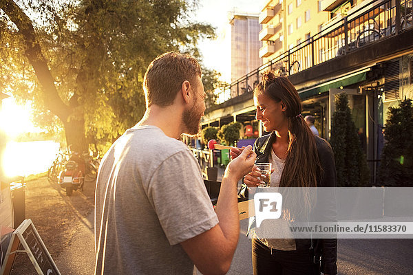 Couple having salad and water while standing on street during sunset