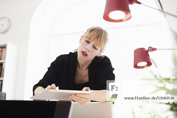 Mittlere erwachsene Geschäftsfrau mit digitalem Tisch im Büro