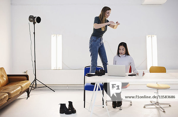 Blogger fotografiert Kollegen mit Laptop am Schreibtisch im Büro