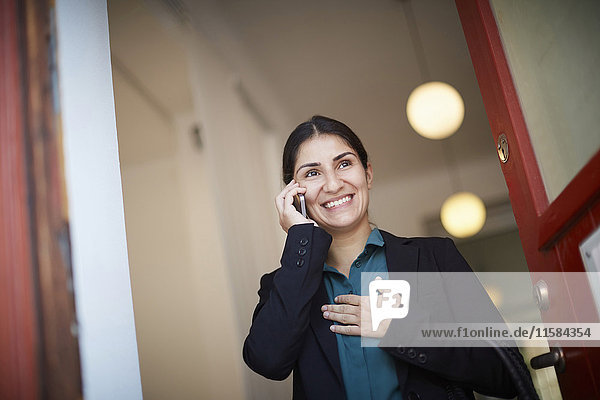 Lächelnde Geschäftsfrau beim Telefonieren im Büro