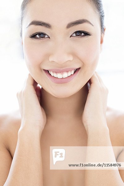 MODEL RELEASED. Young Asian woman with hands touching neck  portrait.