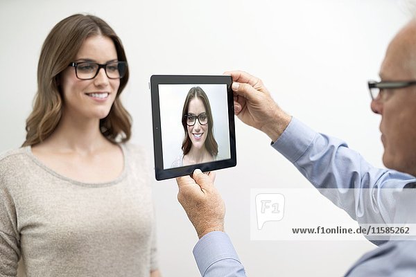 Man holding digital tablet in front of woman's face.