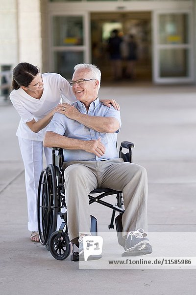 Senior man in wheelchair with care worker.