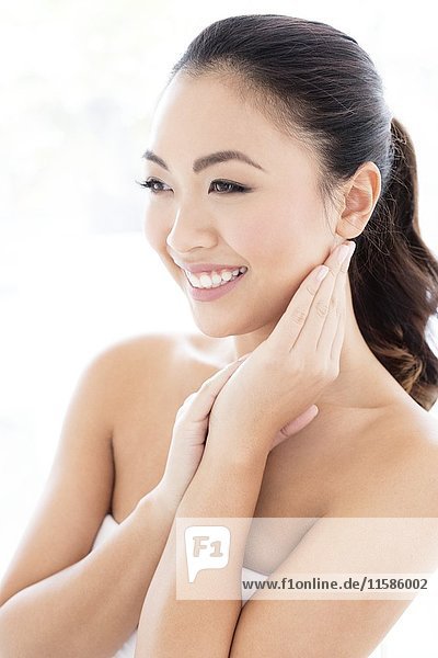 MODEL RELEASED. Young Asian woman with hands touching face  portrait.