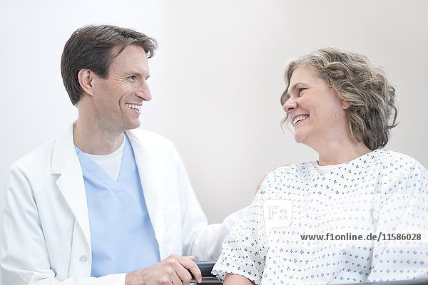 Male doctor smiling at mature female patient.