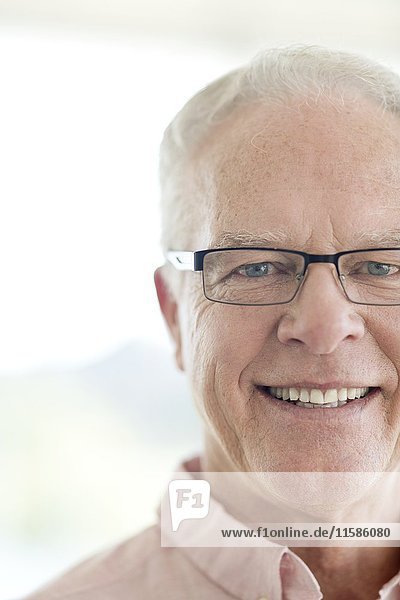 Senior man wearing glasses smiling towards camera.