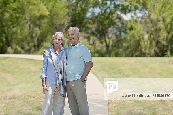 Älteres Paar steht lächelnd im Park.