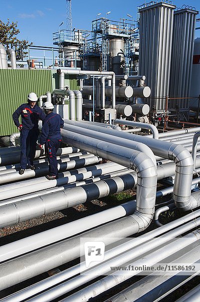 MODELL FREIGEGEBEN. Arbeiter überprüfen Rohrleitungen in einer Öl- und Gasraffinerie.