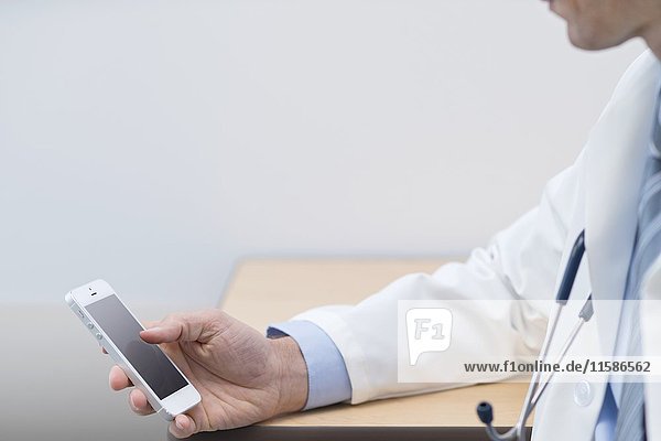 Männlicher Arzt mit Smartphone.