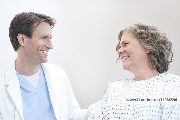 Male doctor smiling at mature female patient.