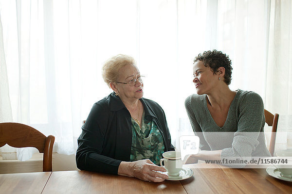 Mutter und erwachsene Tochter sitzen zusammen bei einem Kaffee.