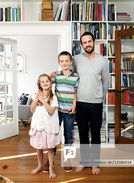 Vater und Familie stehen zusammen im Wohnzimmer  Porträt