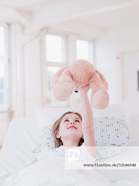 Mädchen im Bett spielt mit Teddybär