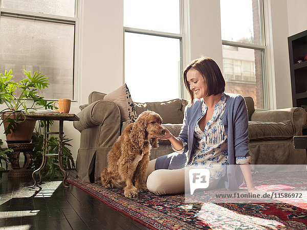Woman stroking pet dog in living room