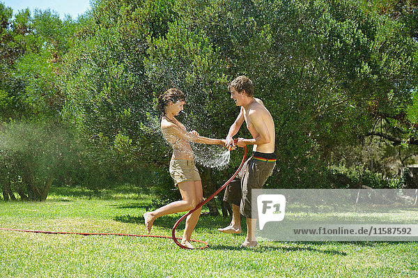 Teenagers playing with water hose