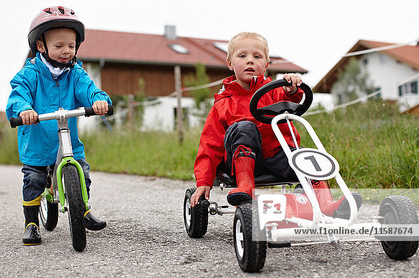 Kleinkinder Jungen fahren Fahrrad und Gokart