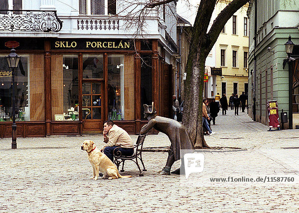 Sitzende Männer und Hund mit Statue