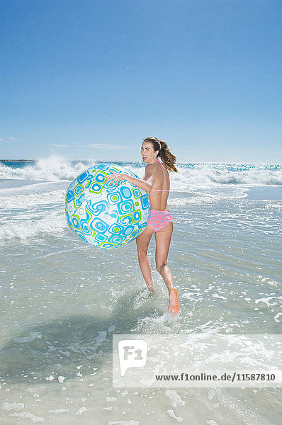 Ein Mädchen rennt mit einem Strandball