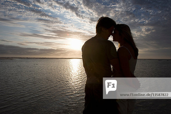 Pärchen küsst sich bei Sonnenuntergang am Strand