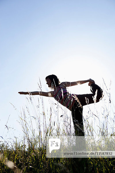 Frau führt Yoga auf der Wiese aus