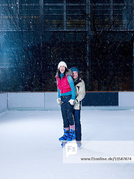Man holding woman above ice while skating