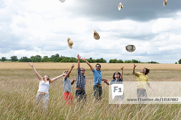 People in field tossing hats in air