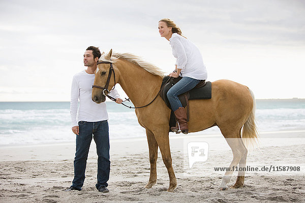 Mann und Frau mit Pferd am Strand