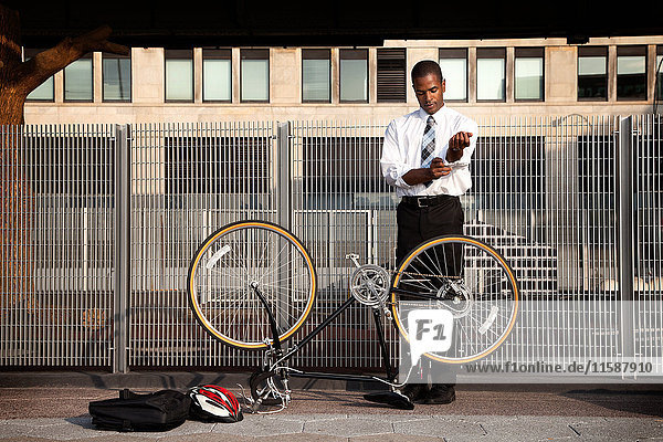 Junger Geschäftsmann rollt Ärmel hoch  um Fahrrad zu reparieren