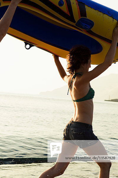 Women carrying inflatable boat on beach