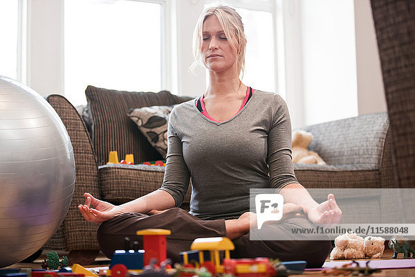 Mittlere erwachsene Frau in Yoga-Pose zu Hause