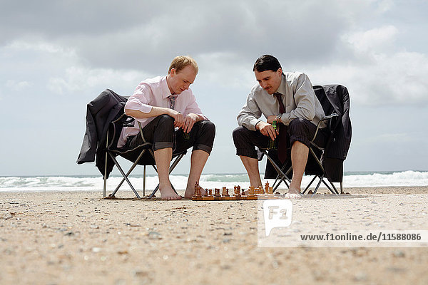 Businessmen playing chess on beach