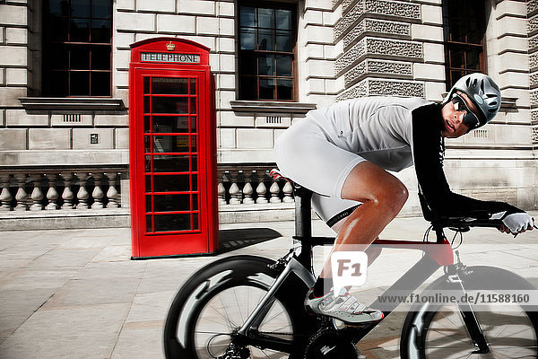 Cyclist cycling past red telephone box