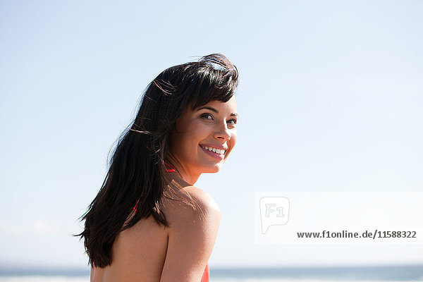 Junge Frau am Strand schaut über die Schulter