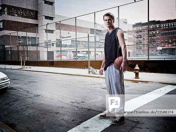 Mann trägt Basketball auf Stadtstraße
