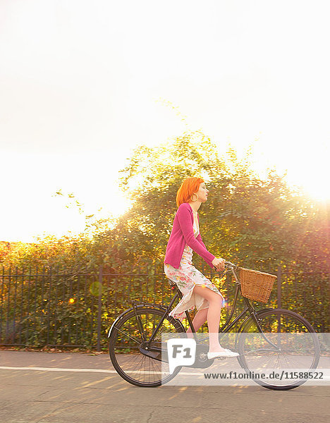 Young redhead woman cycling in park