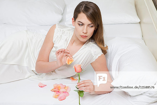 Frau auf Bett  die Rosenblätter zählt