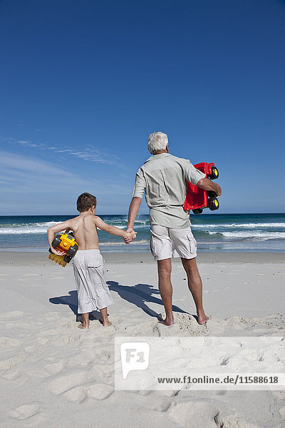 Man holding grandson?s hand on beach