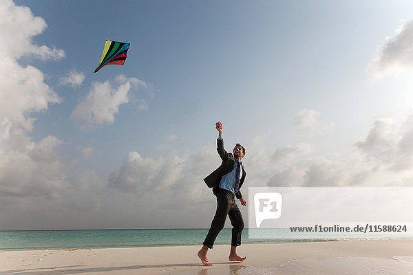 Businessman flying a kite on beach