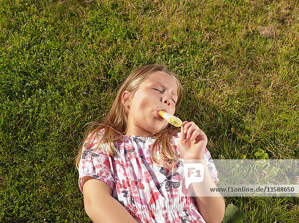 Girl enjoying ice lolly on lawn